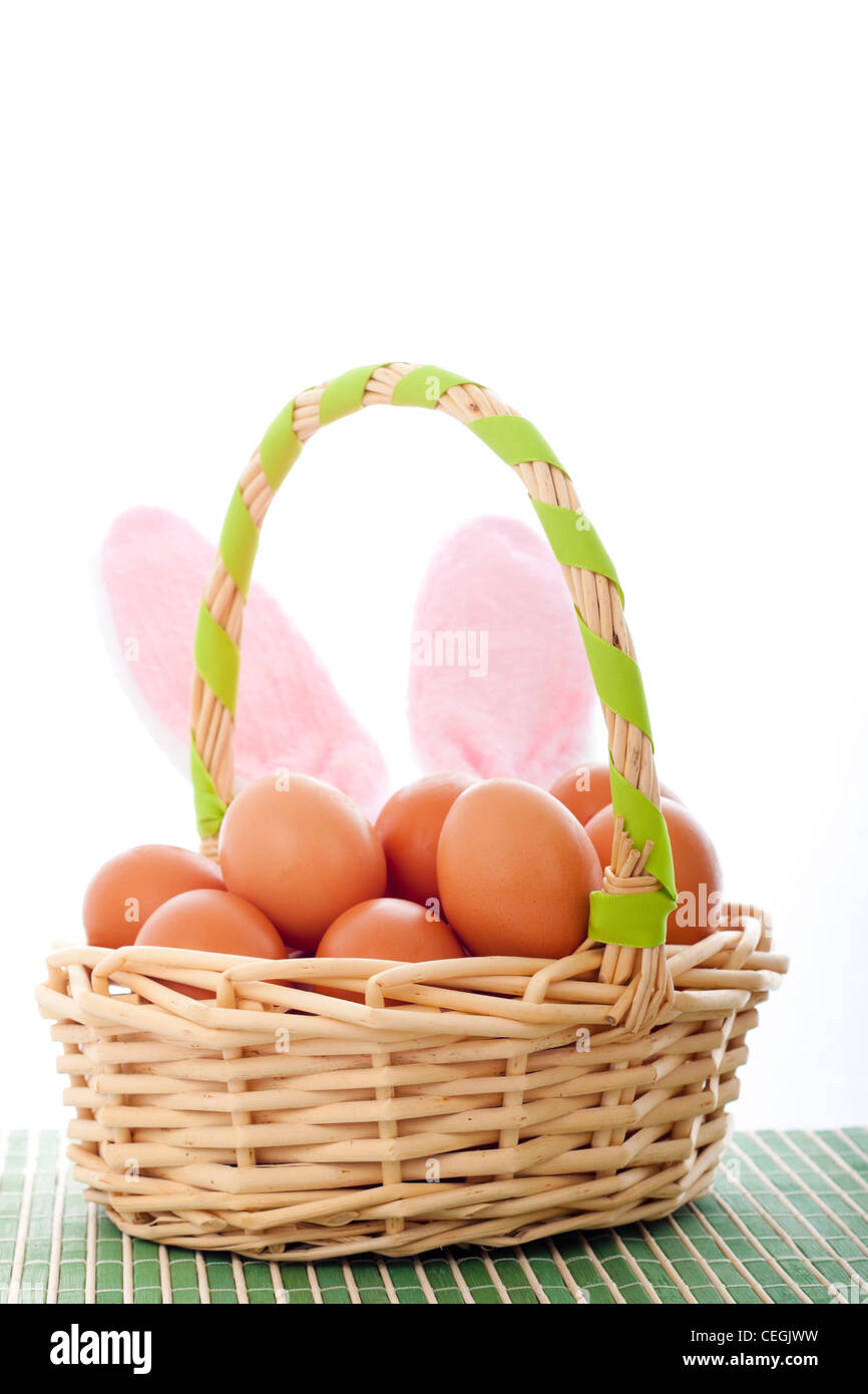 Osterkorb mit Eiern und Hasenohren, Oster-Deko mit Textfreiraum, isoliert auf weißem Hintergrund. Stockfoto