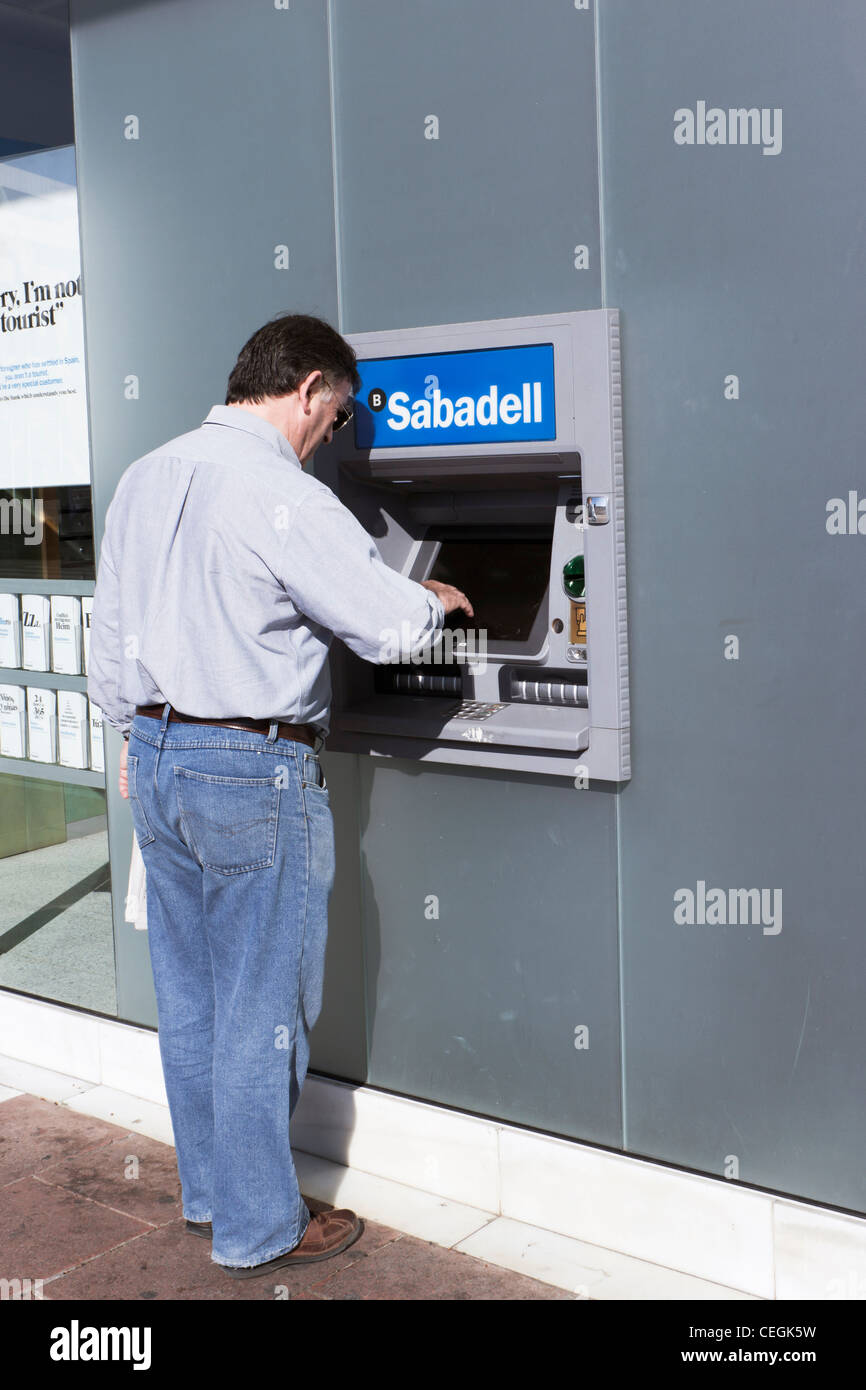 Mann Geldabheben bei Banco Sabdell Cashpoint in Spanien. Stockfoto