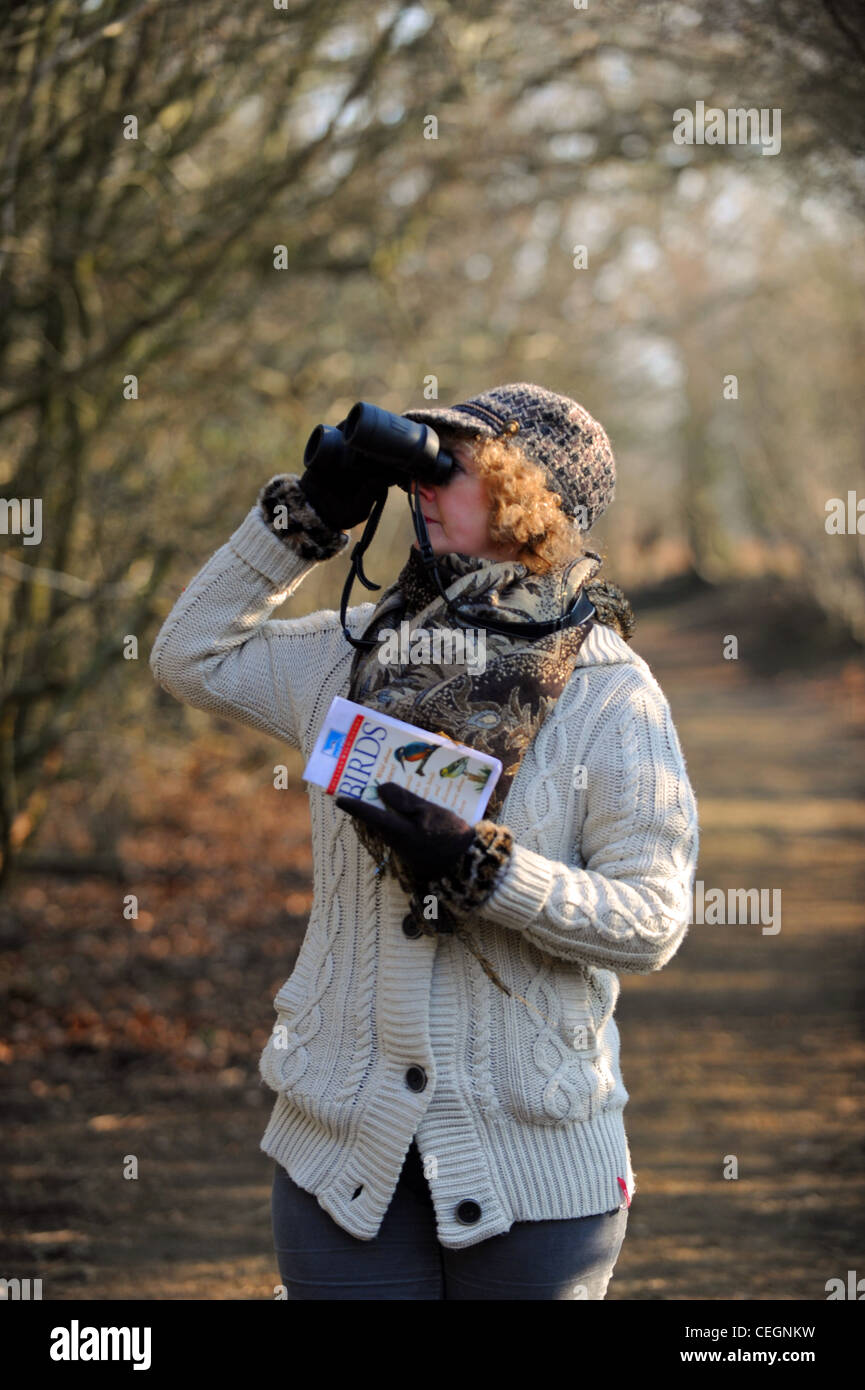 Weibliche Vogelbeobachter mit Fernglas und Identifizierung Buch bei der RSPB Pulborough Brooks Nature Reserve in West Sussex UK Stockfoto
