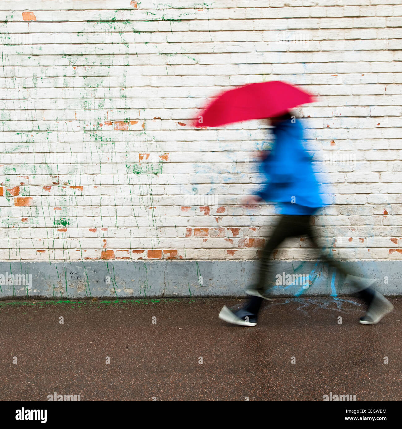Person zu Fuß im Regen mit Regenschirm Stockfoto