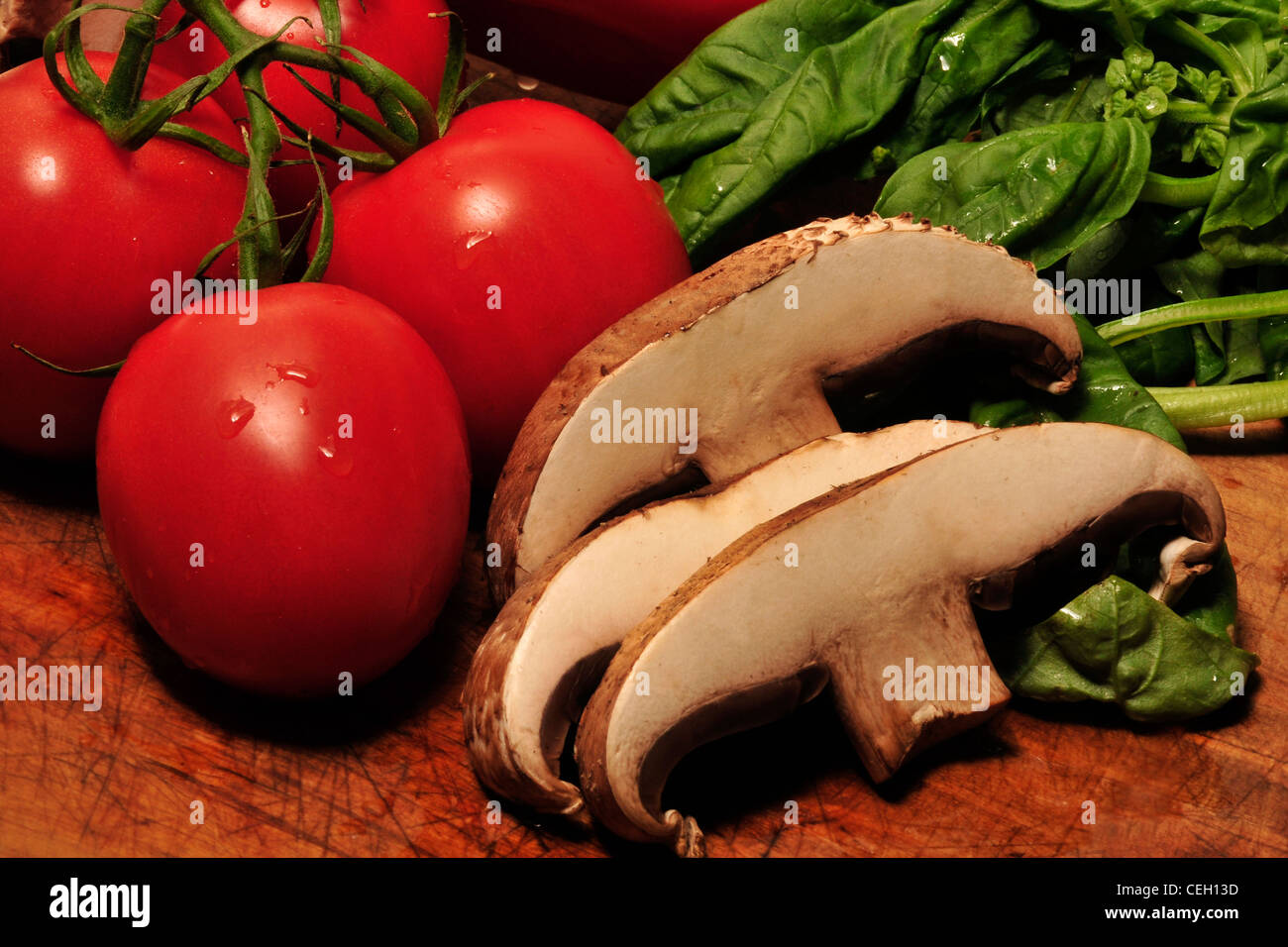 Portabella Pilze, Reben gereifte Tomaten und frischem Basilikum auf ein Schneidebrett. Stockfoto