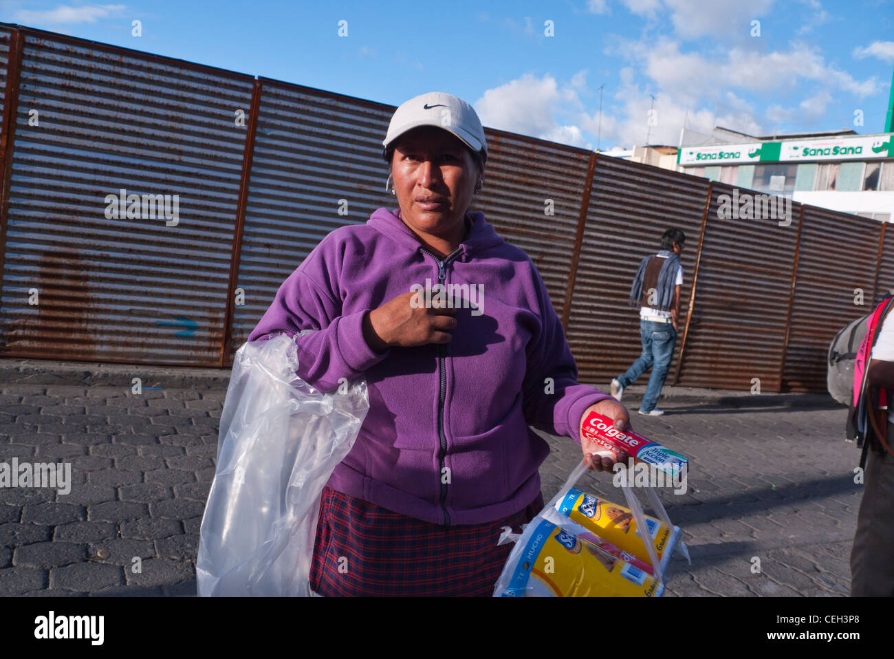 Eine 40-50 Jahre alten Hispanic Frau überquert eine Straße in Latacunga, Ecuador ihre Einkaufstaschen im späten Nachmittag Licht. Stockfoto