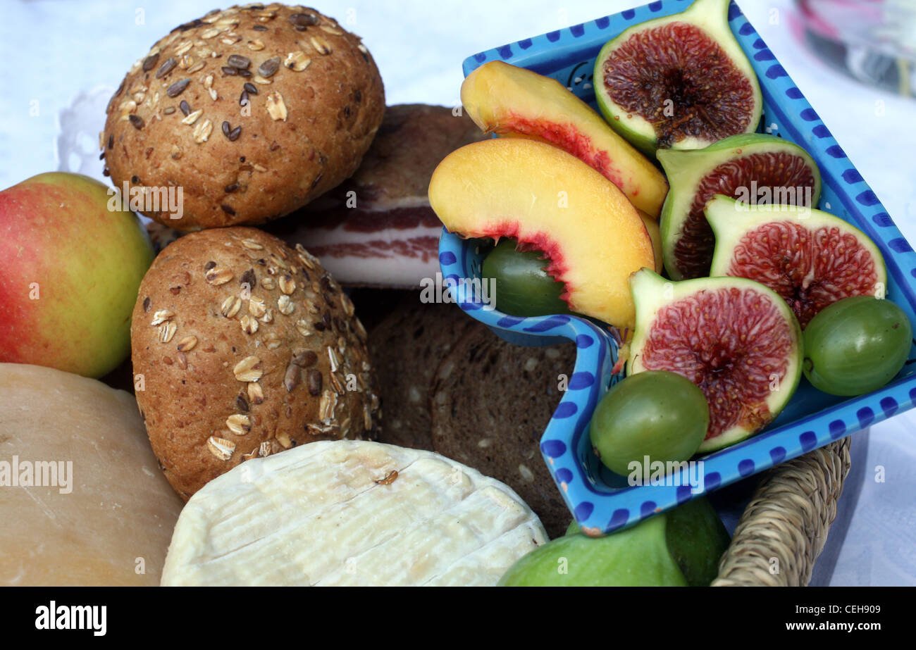 Rustikale Stillleben mit Brot, Käse, Speck und Feigen in einem Weidenkorb Stockfoto