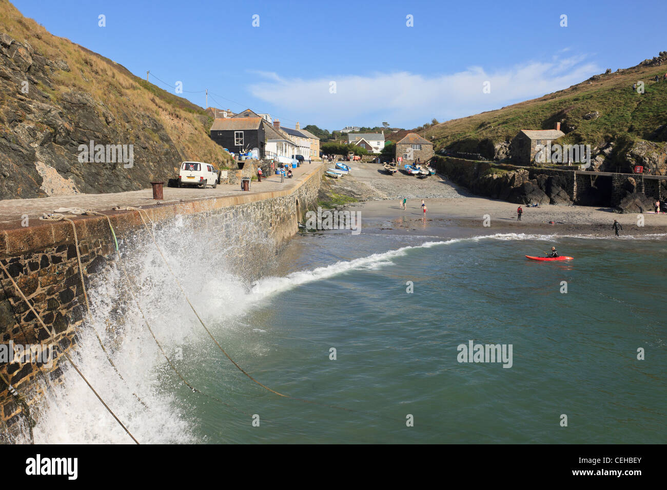 Wellen schlagen auf einem Kai auf ankommende Gezeiten alten Fischerdorf an der Küste Cornish. Mullion Cove Cornwall England Großbritannien Stockfoto