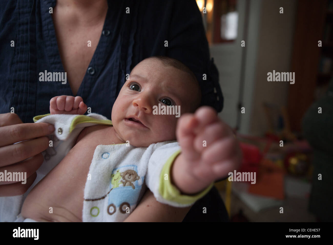 Reflexive Strecke von neugeborenen Babys Arm als Mutter versucht, ihre Kleidung zu ändern. Stockfoto