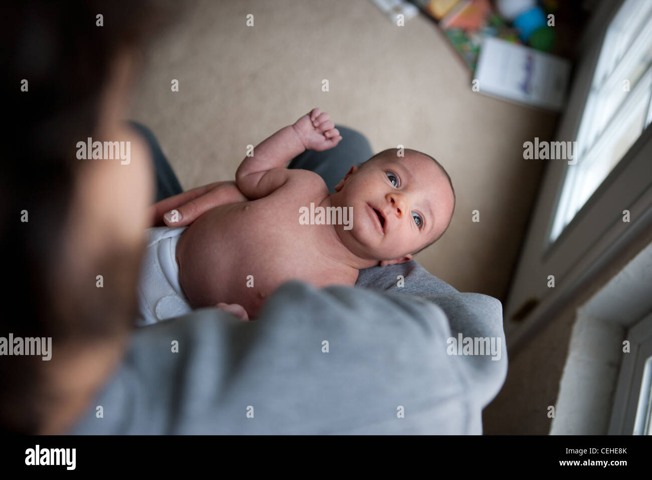 Zwei Monate altes Mädchen von ihrem Vater, betrachtet man Fensterlicht gehalten. Stockfoto