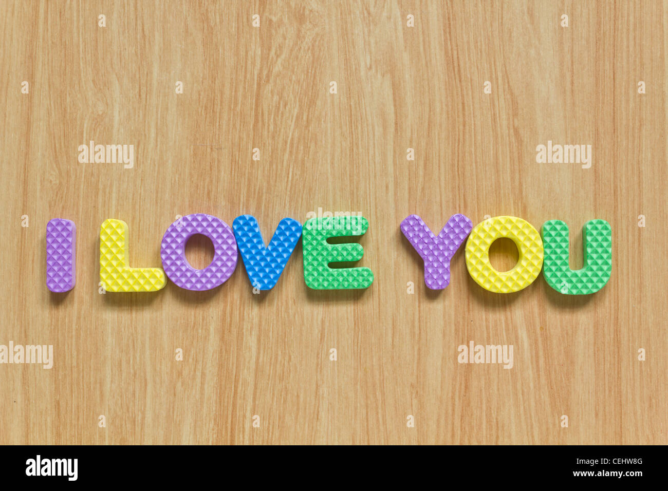 Bunte Buchstaben mit "Ich liebe dich' isoliert auf Holzstruktur