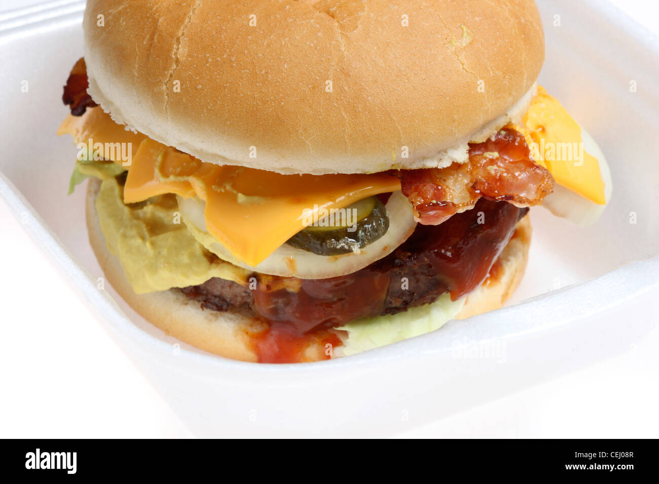 Ernährung, Fast-Food. Hamburger, Fleischkäse mit Zwiebeln, Gurken, Senf, Ketchup, Brot Roll, Käse und Speck. Stockfoto