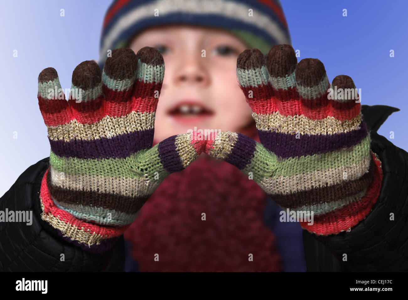 kleine Mädchen im Studio mit behandschuhten Händen bis die Kamera mit blauen kalten Hintergrund Stockfoto