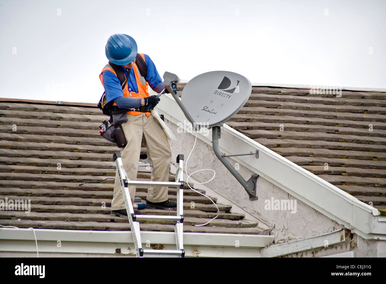 Ein Techniker installiert eine Satellitenschüssel auf dem Dach eines neu erworbenen Hauses in Laguna Niguel, CA Stockfoto