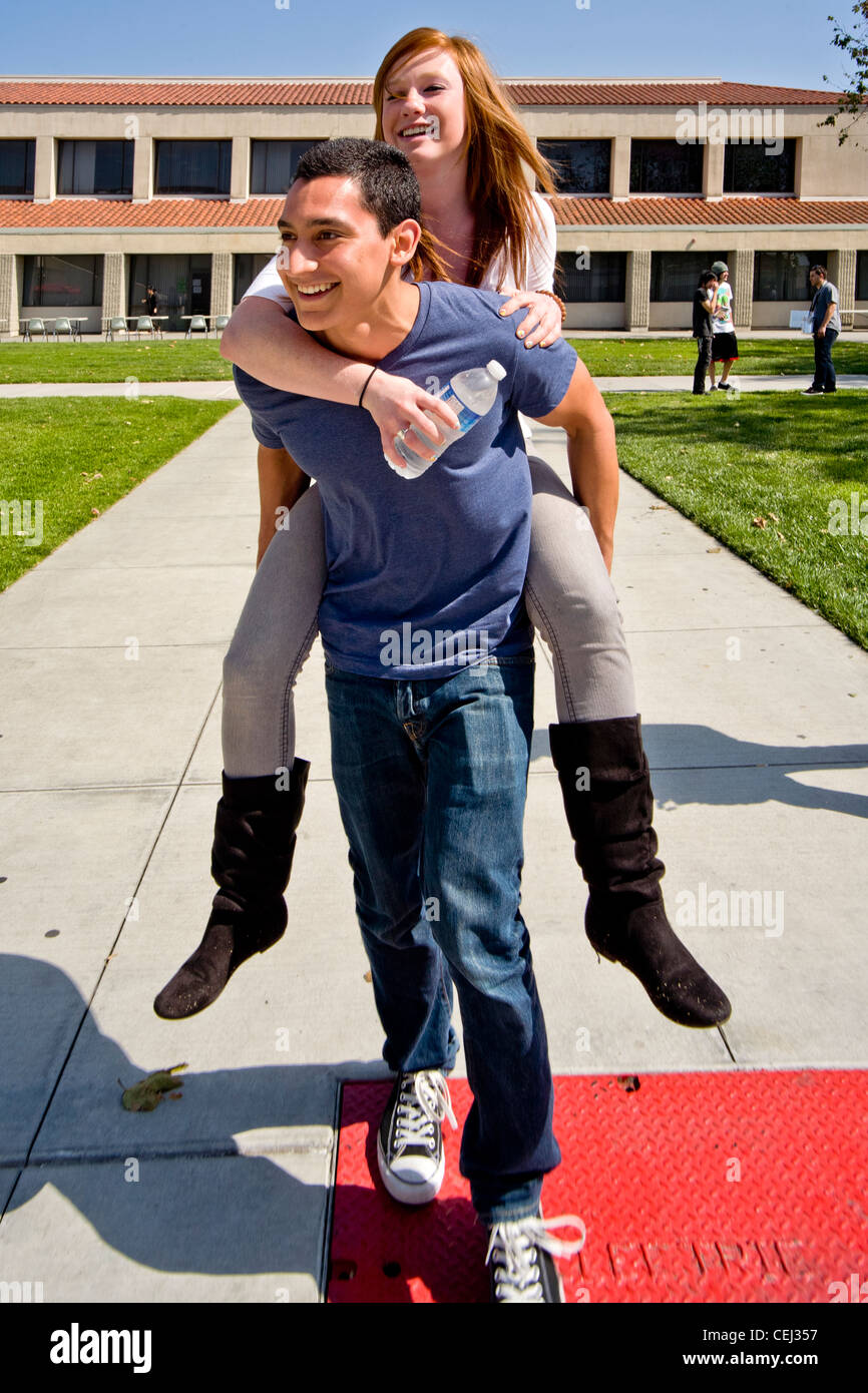 Hispanic Student trägt seine kaukasischen Freundin Huckepack über den Campus der Saddleback College in Mission Viejo, Kalifornien. Stockfoto