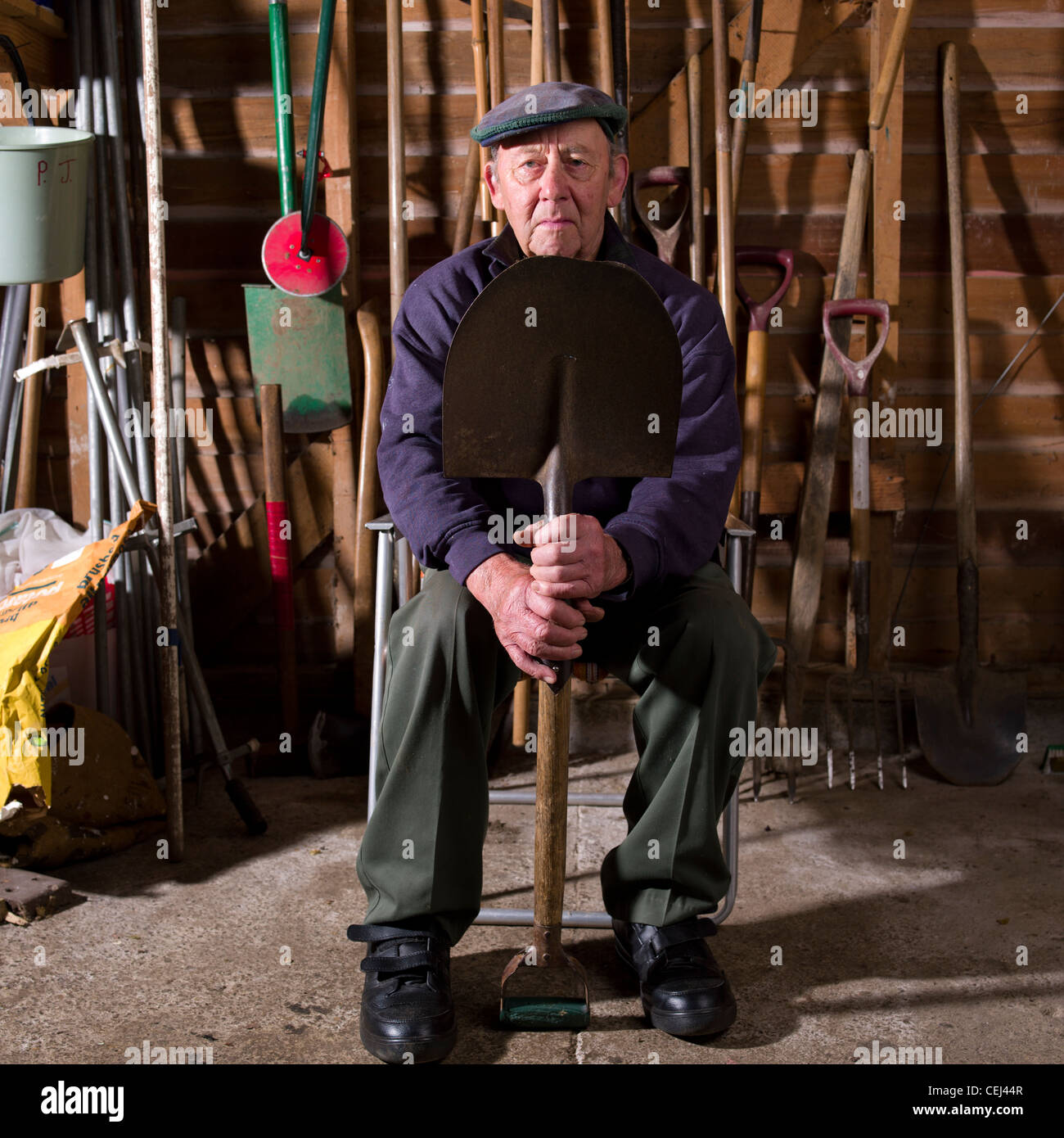 ältere Mann in seine 80er Jahre sitzen im Stuhl halten schieben, l in  seinem Geräteschuppen Stockfotografie - Alamy
