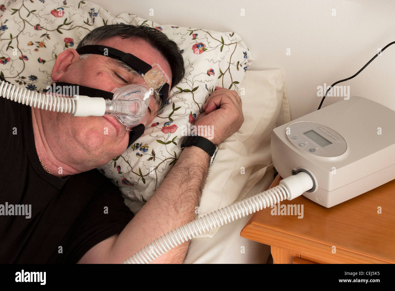 Mann mit einer CPAP-Maske und Maschine verwendet für die Behandlung von Schlafapnoe. Stockfoto