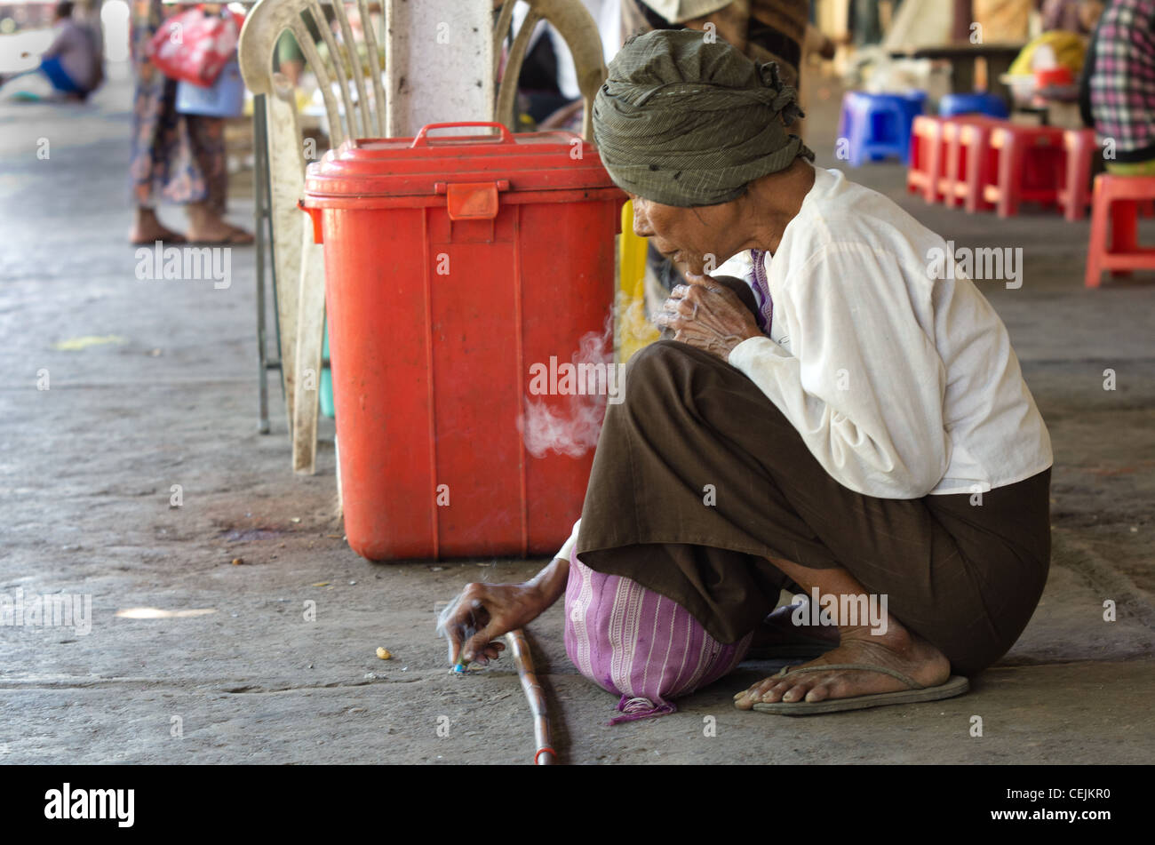 Mann Rauchen während des Wartens auf einen Zug im Bahnhof von Rangun, Burma Stockfoto