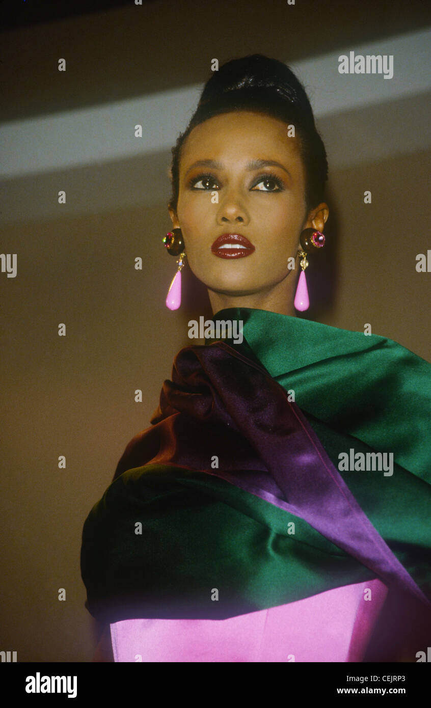 s Fashion Model, Iman Haare vom Gesicht in Haartolle tragen große Ohrringe lila Tropfen, grüne und lila Satin wrap-around Schultern Stockfoto