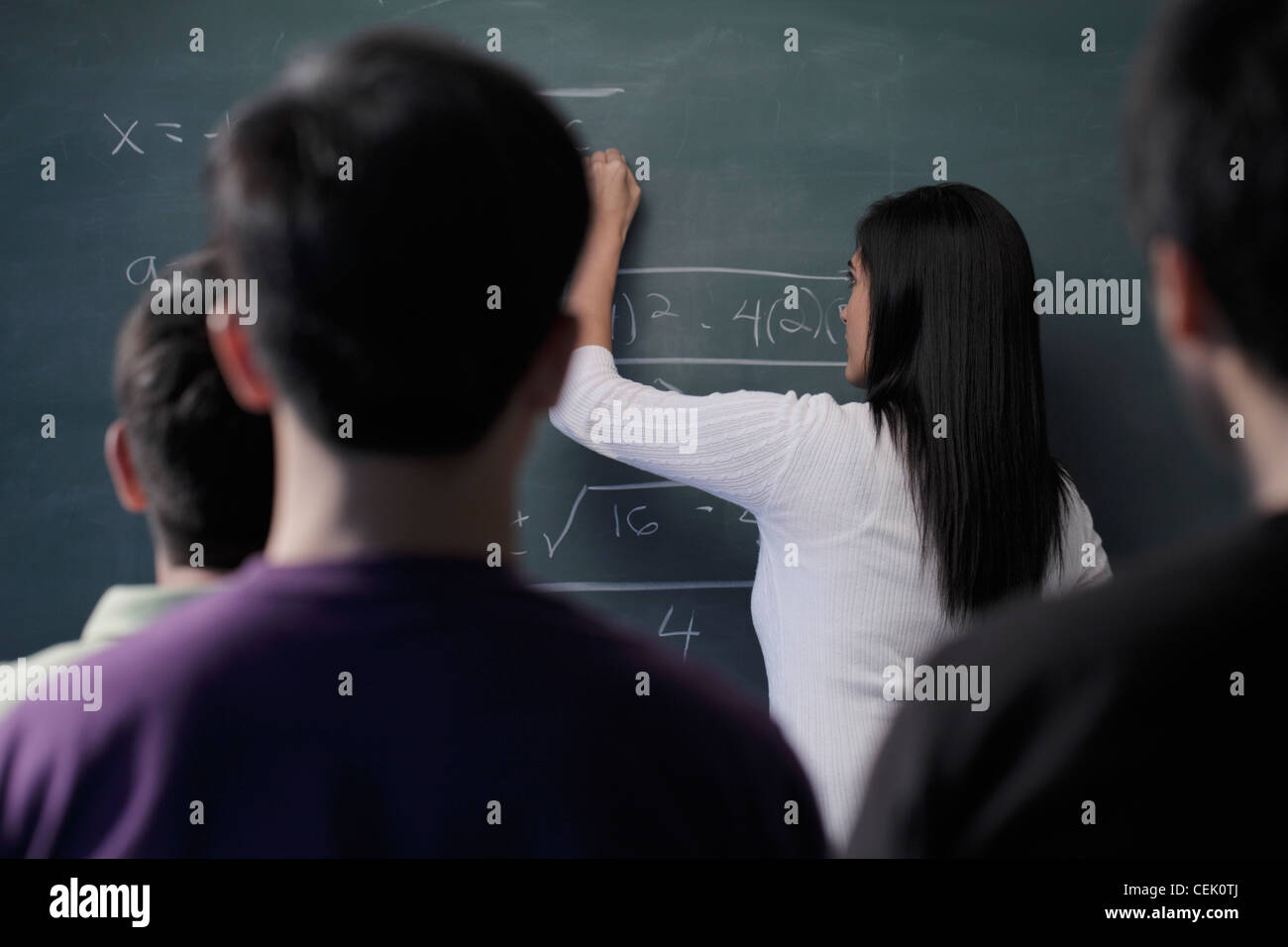 Rückansicht des Studenten gerade Lehrer an Tafel schreiben Stockfoto