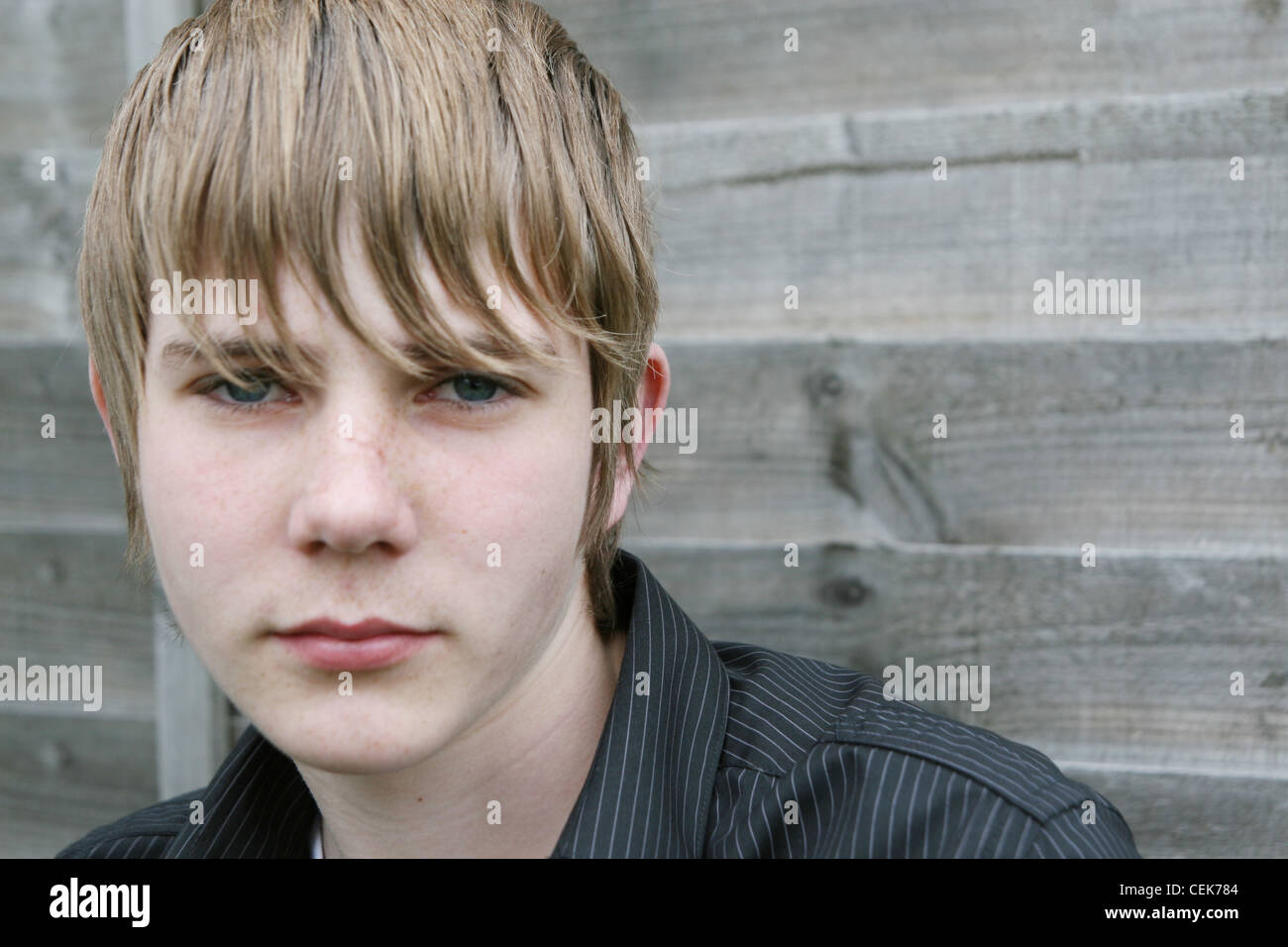 Teenager männlich lehnte sich gegen einen Holzzaun, trägt Blue Jeans