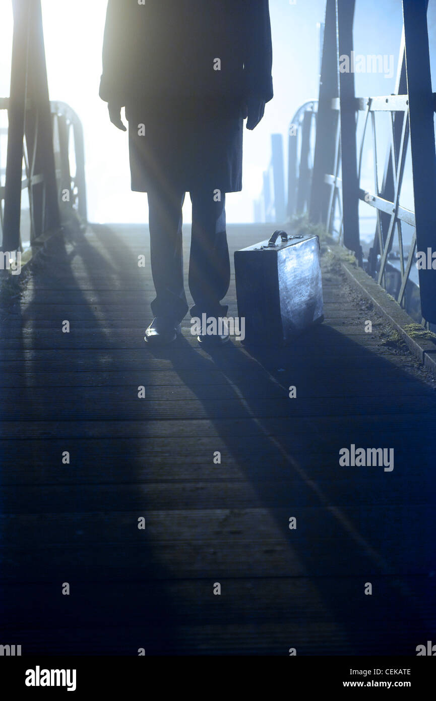 Mann mit Fall stehen auf einer Brücke im Nebel Stockfoto