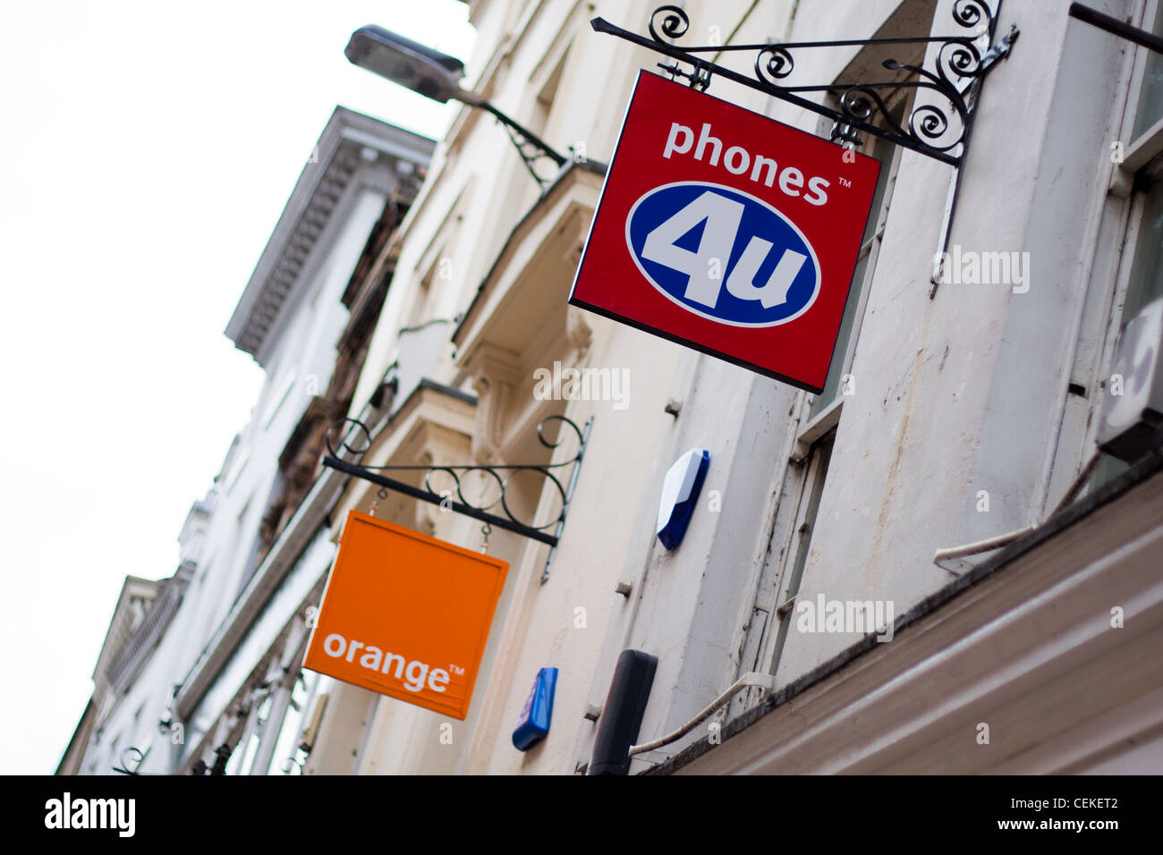Wettbewerb im Bereich der mobilen Telekommunikation Telefone Industrie mit Orange, 4 Telefone Sie und Vodafone Zeichen außerhalb ihrer Geschäfte. Stockfoto