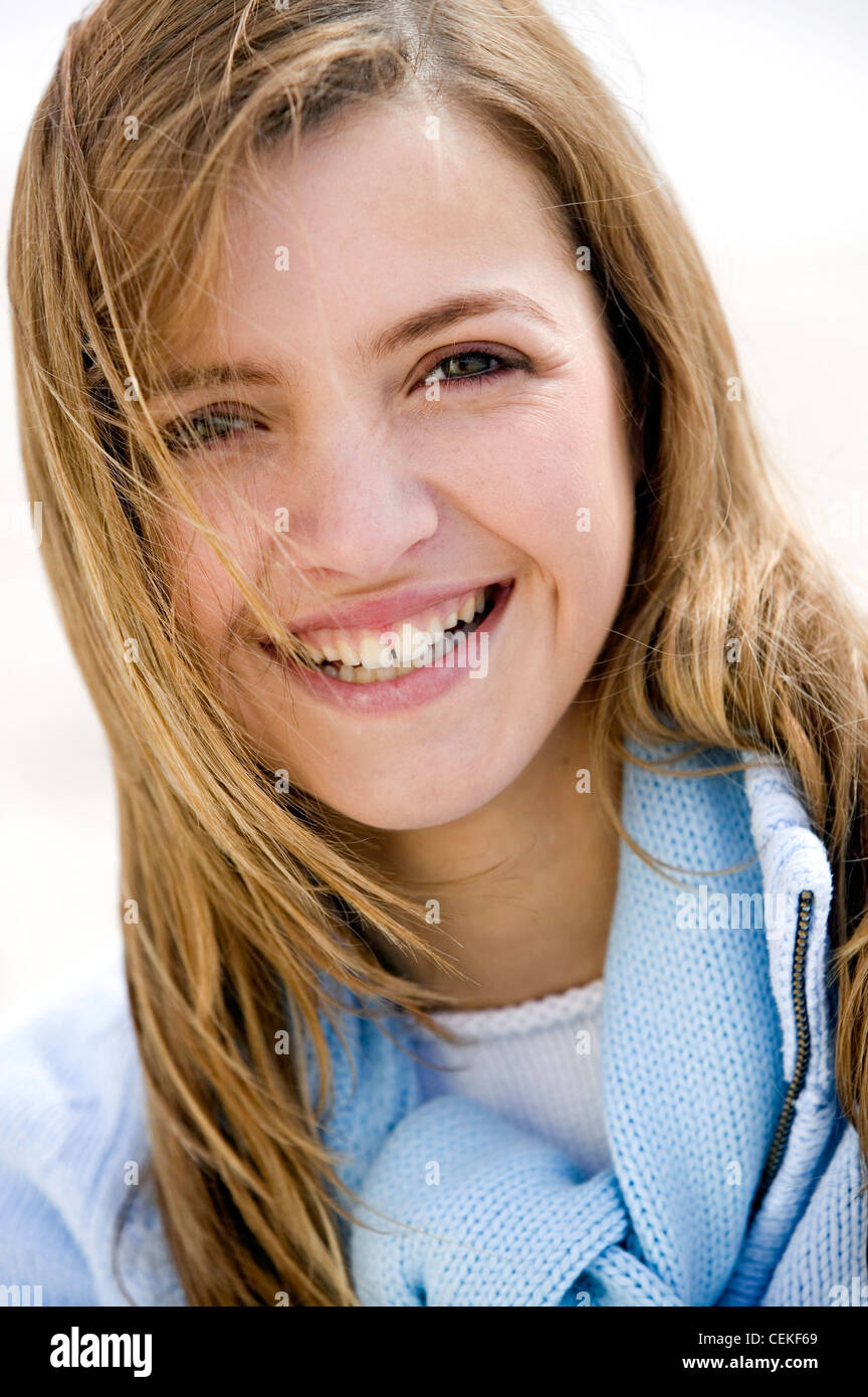 Nahaufnahme von Frauen mit langen blonden Haaren tragen blass blauen Pullover auf Kamera Lächeln zeigt Zähne Stockfoto