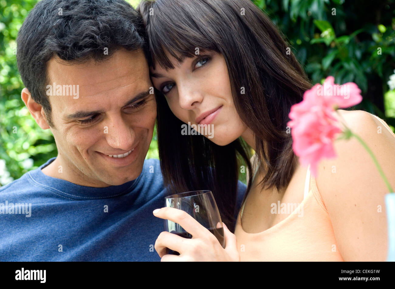 Paar, sitzen im Garten, weibliche Schulter Länge gerade brünette Haare tragen Pfirsich Trägertop auf die Kamera die Hälfte Stockfoto