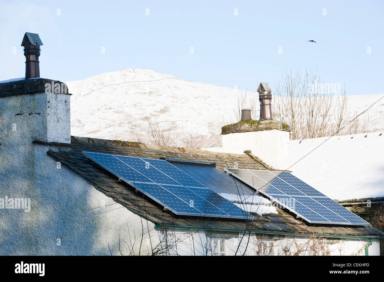 Sonnenkollektoren auf einem Haus Dach in Troutbeck im Schnee, Lake District, Großbritannien. Stockfoto
