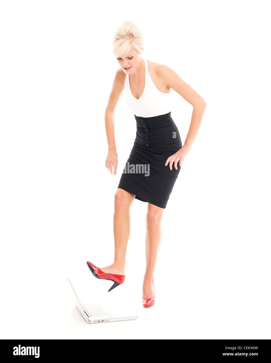 Frau trägt einen schwarzen high-Waist-Rock, patent einen weißen Bikini Oberteil und rot Schuhe dabei, ihre Ferse in einen Laptop zu graben Stockfoto