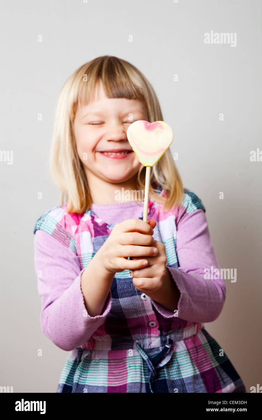 Niedliche kleine Mädchen mit einem Herz-Form-Lutscher. Studio gedreht. Stockfoto