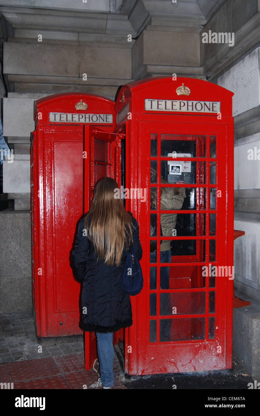 Frau wartet auf eine rote Telefonzelle der UK in London Stockfoto