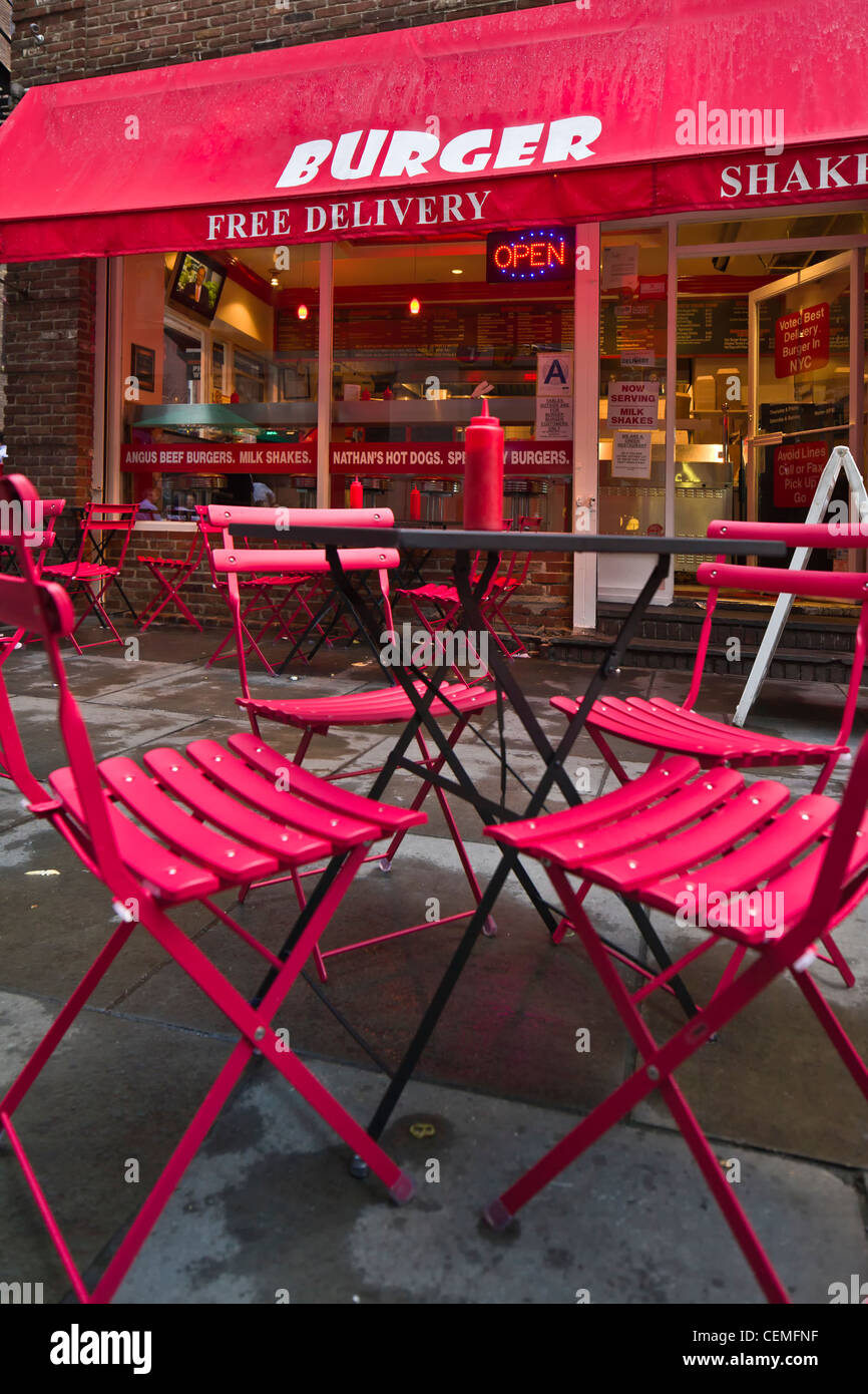 Ein Burger-Restaurant mit roten Stühlen und Tischen in der vor dem Geschäft. Stockfoto
