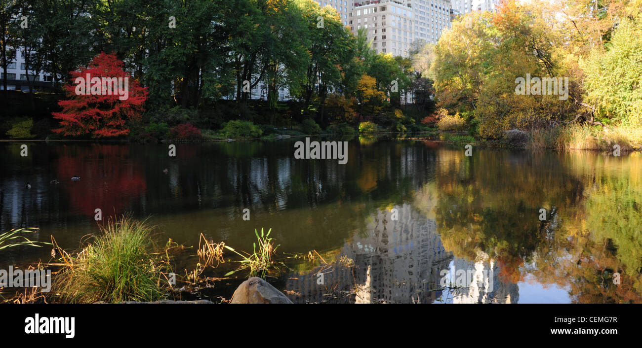 Sonnige Aussicht in Richtung West 59th Street, rote Herbst Bäume, reflektierenden Wasser den Teich, Central Park South New York Wolkenkratzer Stockfoto