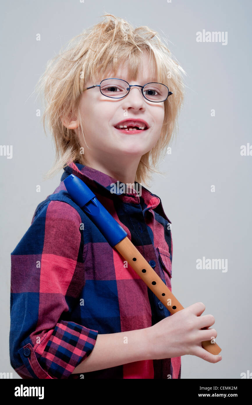 Junge mit fehlenden Milchzähne und Gläser halten seine Querflöte - isoliert auf grau Stockfoto