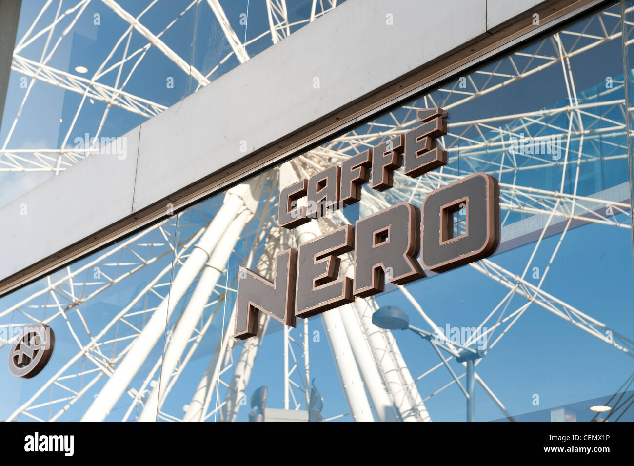 Caffé Nero Coffee Shop-Logo auf Glas-Fenster mit Reflexion der Wheel of Manchester im Hintergrund (nur zur redaktionellen Verwendung). Stockfoto