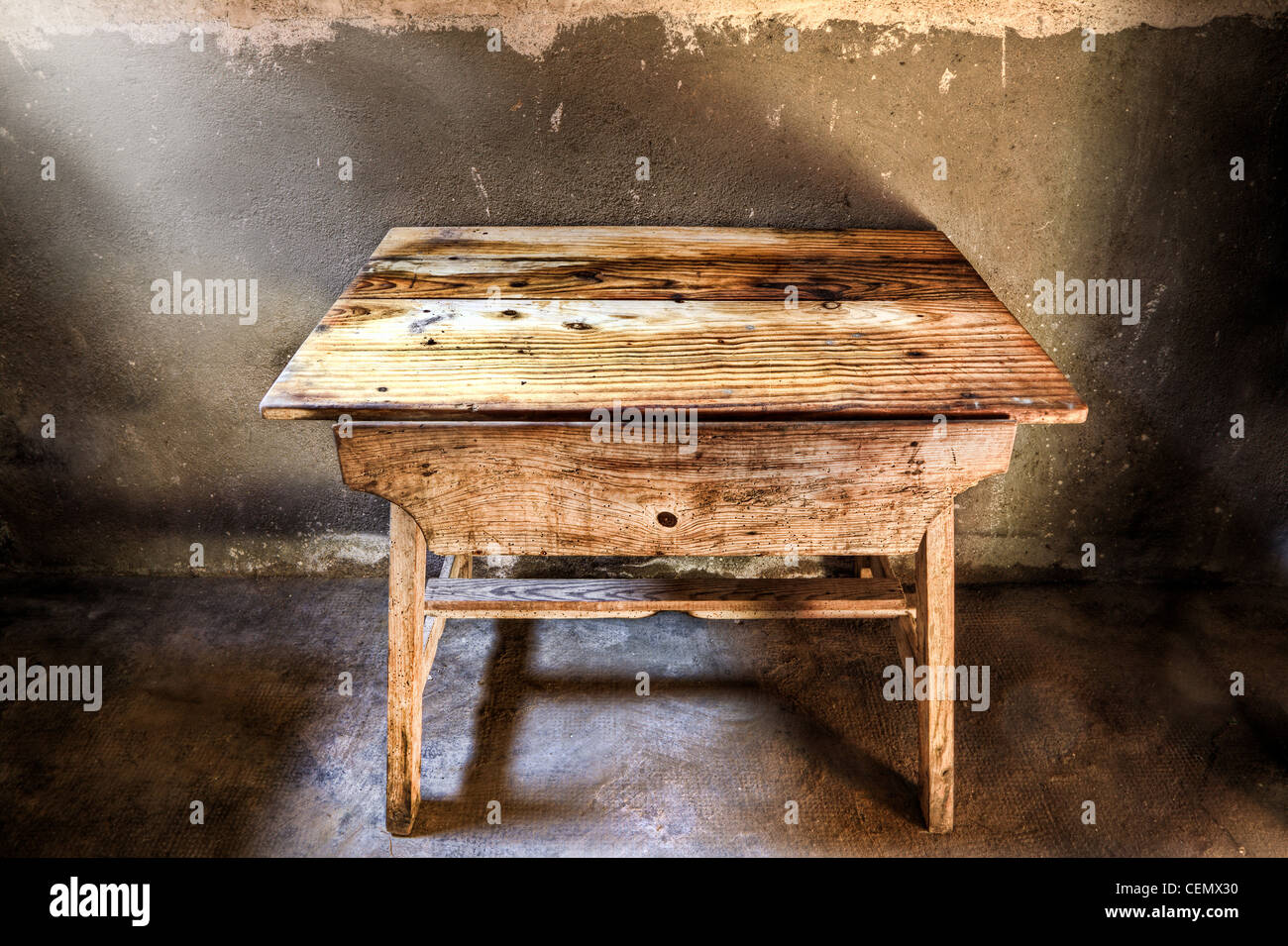 Alten Holztisch in einem abgedunkelten Raum mit Licht aus dem Fenster beleuchtet. Stockfoto