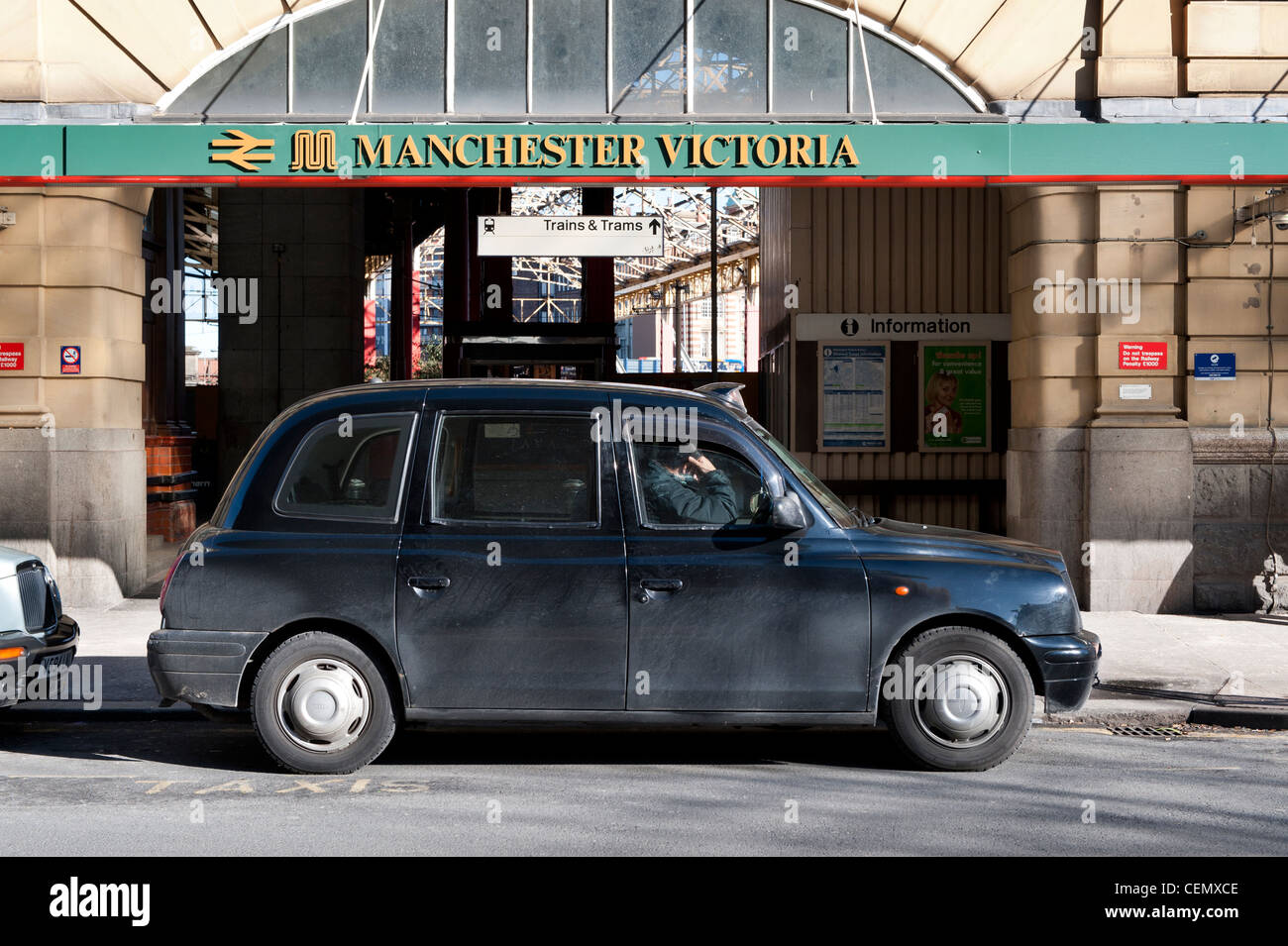 Ein Taxifahrer sitzt, wartet auf seinen nächsten Kunden vor Manchester Victoria Rail Bahnhof Zug. Stockfoto