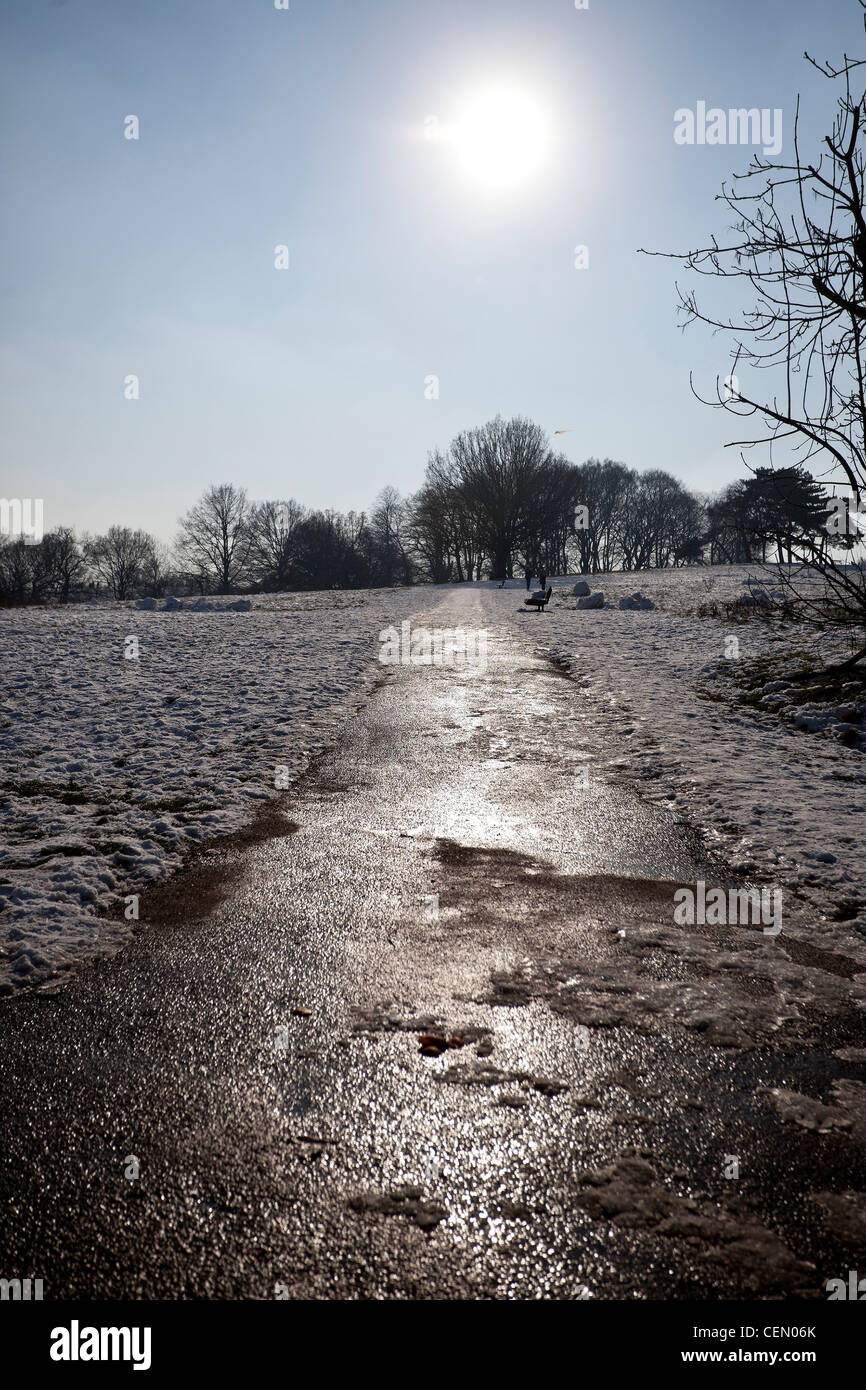 Gefrorene asphaltierten Weg durch verschneite Feld, Hampstead Heath, London, England, UK Stockfoto