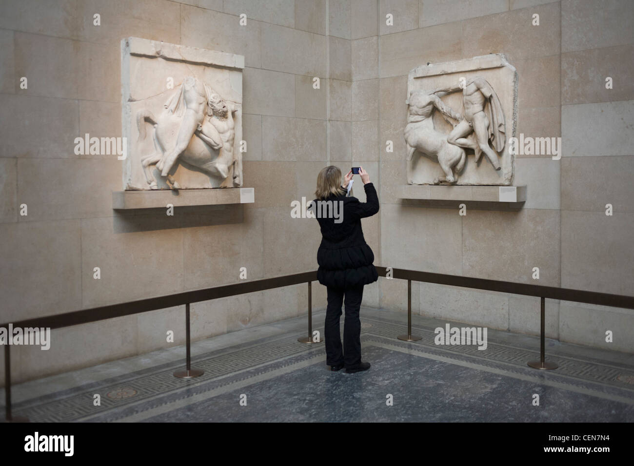 Frau fotografiert die antiken griechischen Parthenon-Metope, auch bekannt als Parthenon (Elgin) Marbles im British Museum. 92 Metope waren rechteckige Platten, die über den Säulen des Athener Parthenon-Tempels aufgestellt wurden und Szenen aus der griechischen Mythologie darstellen. Stockfoto