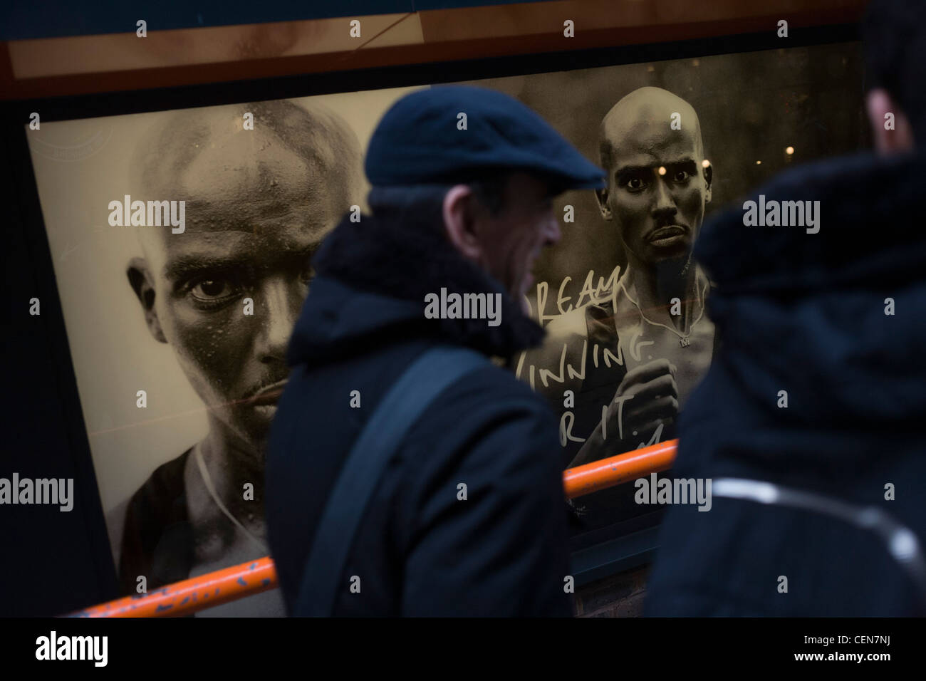 Passanten laufen vorbei an britischer Leichtathlet Mo Farah Gesicht schmückt Plakate außerhalb einer Nike-Schaufenster im Londoner Westend. Stockfoto