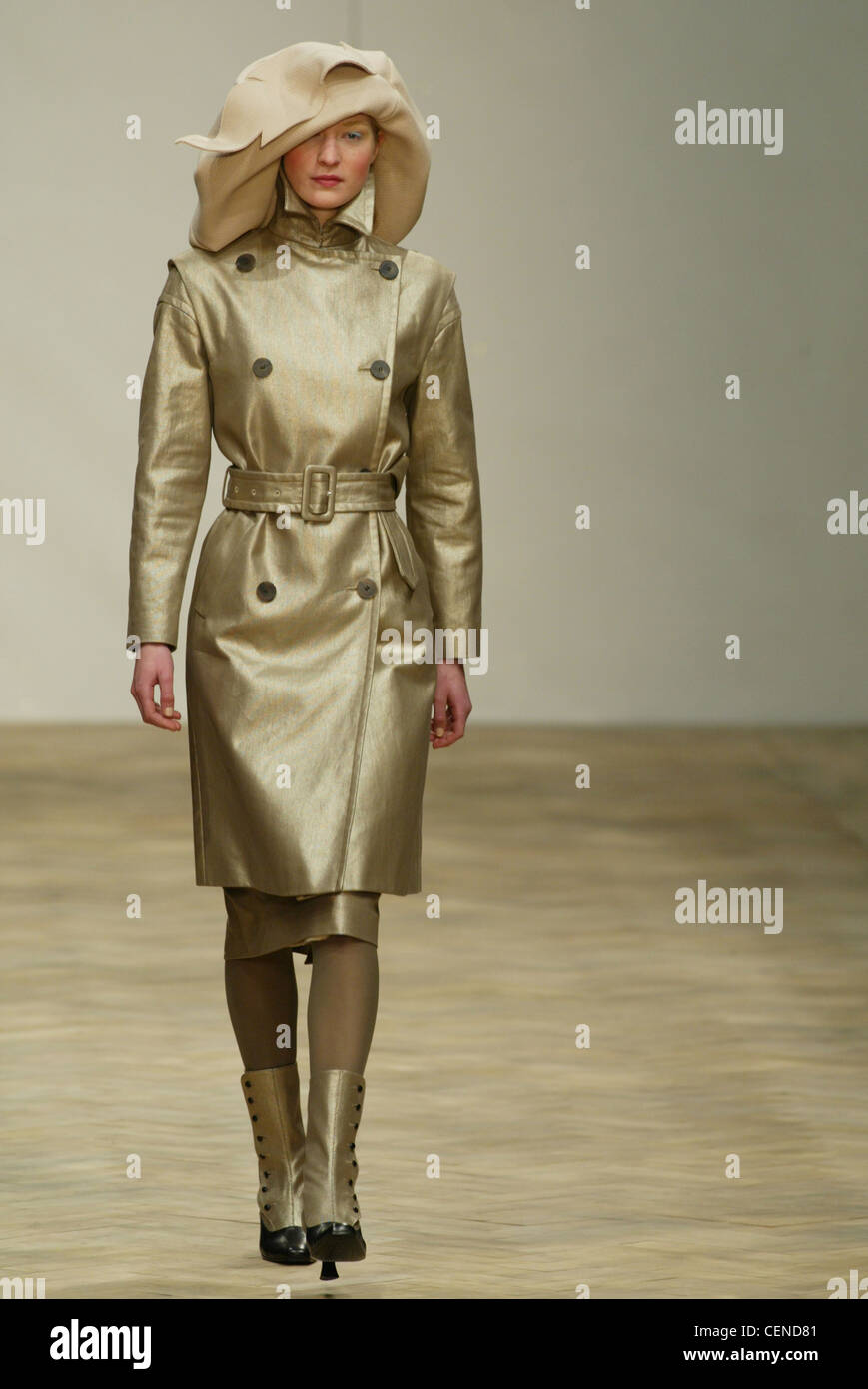 Gibo-London-Herbst-Winter-Modell tragen große Beige Diskette Filzhut, metallisches gold Mantel Gürtel an der Taille, metallisches gold Knie Stockfoto