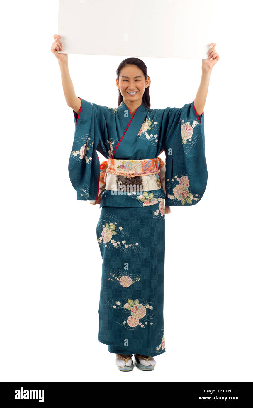 Voller Länge des Lächelns japanischer Kimono Frau hält eine leere Plakatwand mit textfreiraum für Text auf weißem Hintergrund isoliert Stockfoto