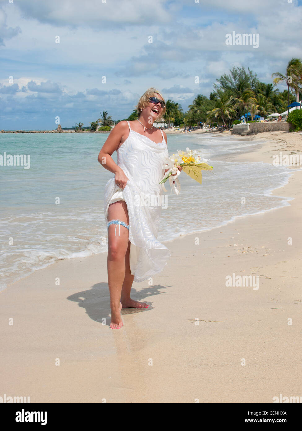 Glücklich lachende Braut barfuß am Strand von Jamaika Hochzeit Stockfoto