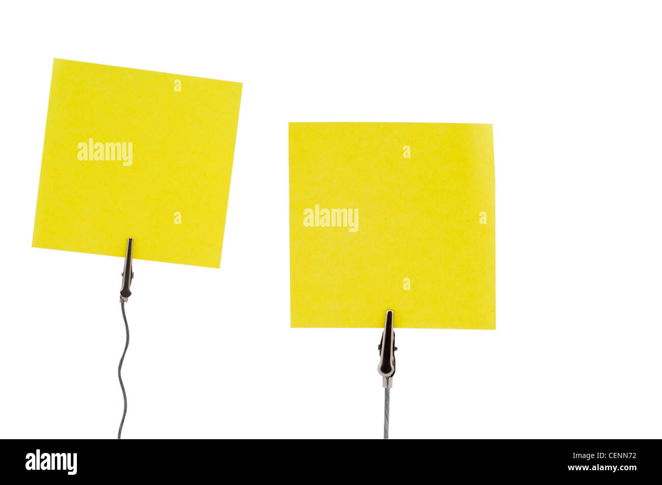 Zwei gelbe Haftnotizen, die auf Metallhalterungen gesteckt werden. Ideal für geschäftliche Erinnerungen, Bürokommunikation und Visualisierung von Unternehmen. Stockfoto