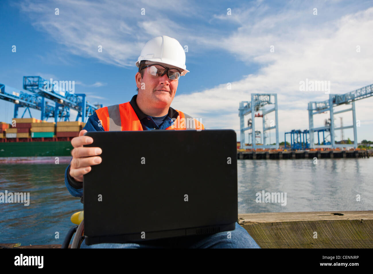 Transport-Ingenieur im Rollstuhl Datenaufzeichnung auf Laptop im Verschiffungshafen Stockfoto