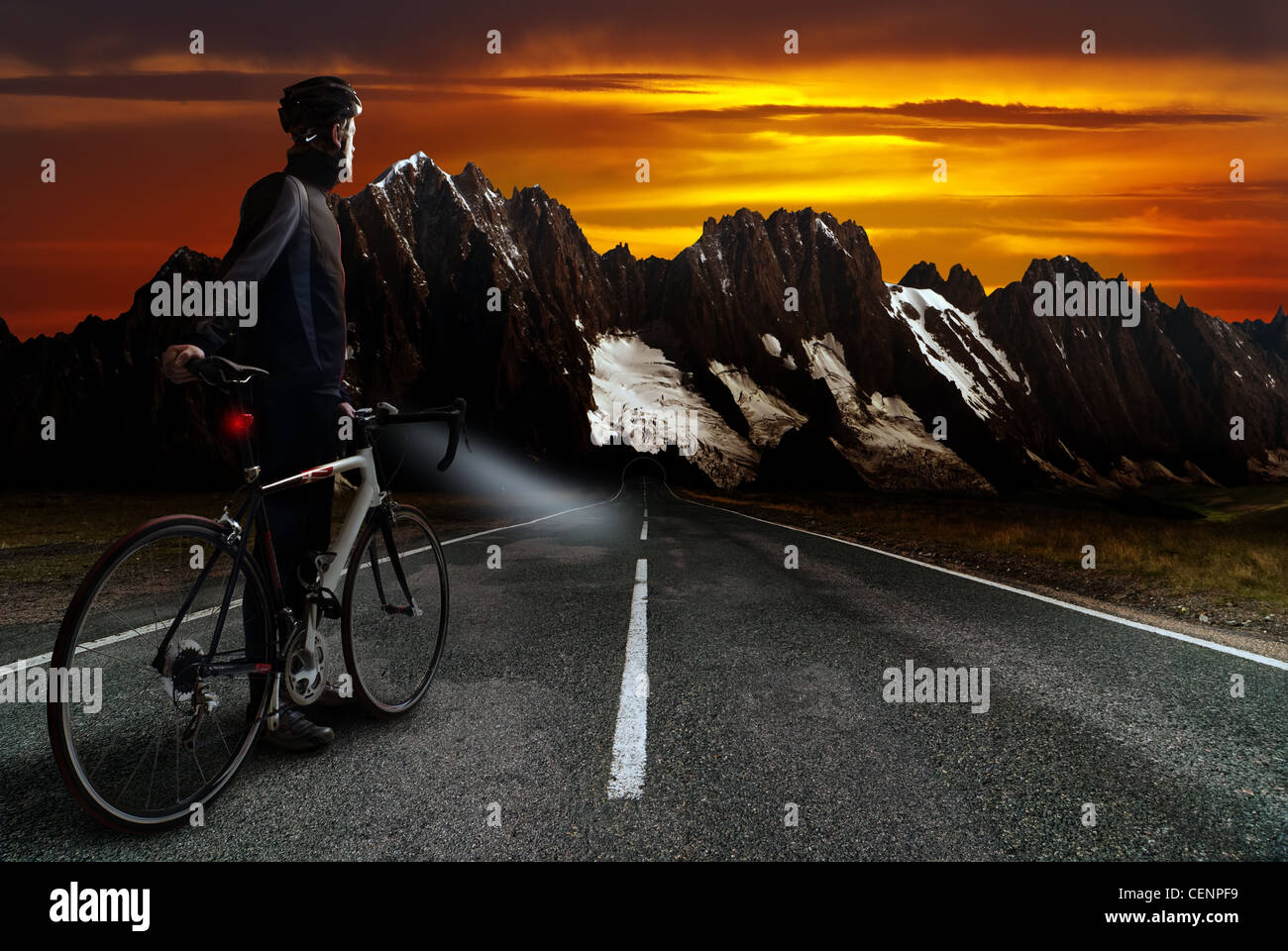 ein Radrennfahrer steht auf der Straße vor der Bergregion mit Einbruch der Dunkelheit Stockfoto