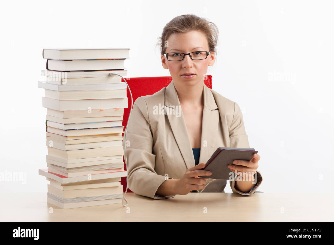 Geschäftsfrau mit Ebook-Reader, der mit einem Stapel Bücher verbunden ist Stockfoto