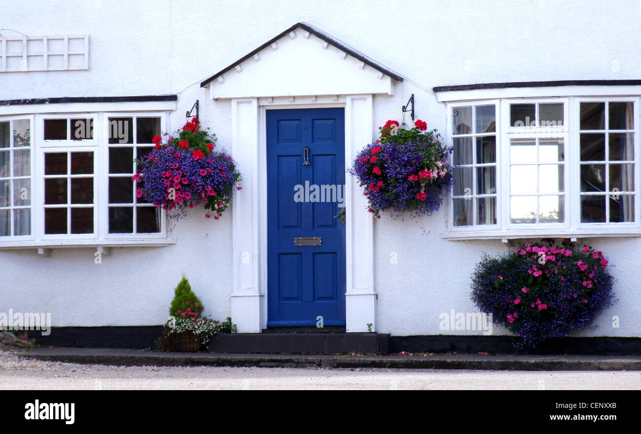 Blaue Eingangstür einer Hütte mit hängenden Körben beidseitig weiß lackiert Stockfoto