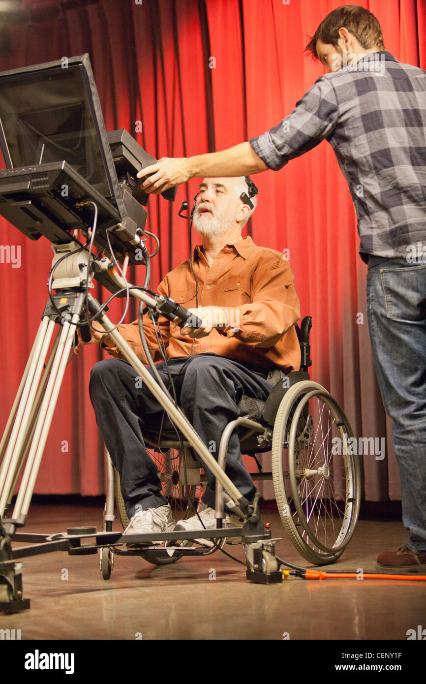 Mann im Rollstuhl mit Muskeldystrophie auf eine TV-Kamera mit dem Produzenten in einem TV-studio Stockfoto