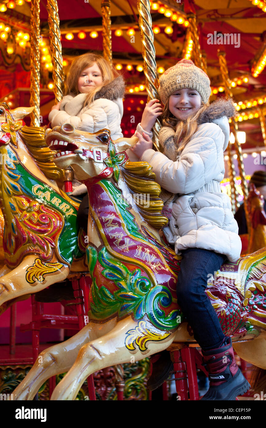 Kinder auf Merry Go Round Messegelände fahren. Stockfoto