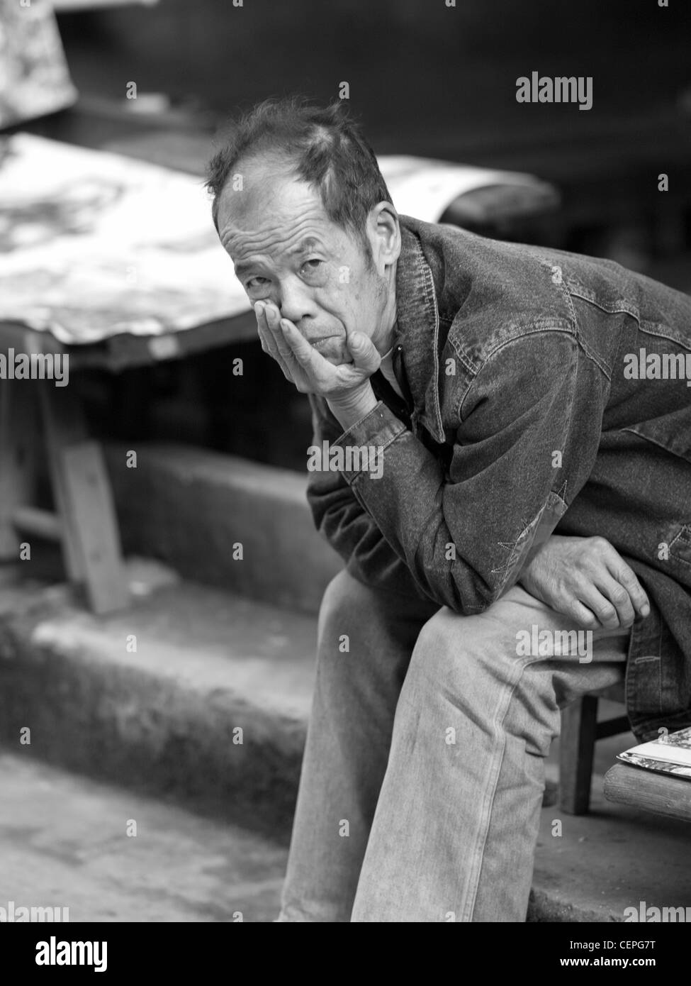 Mann sitzt im freien In China Stockfoto