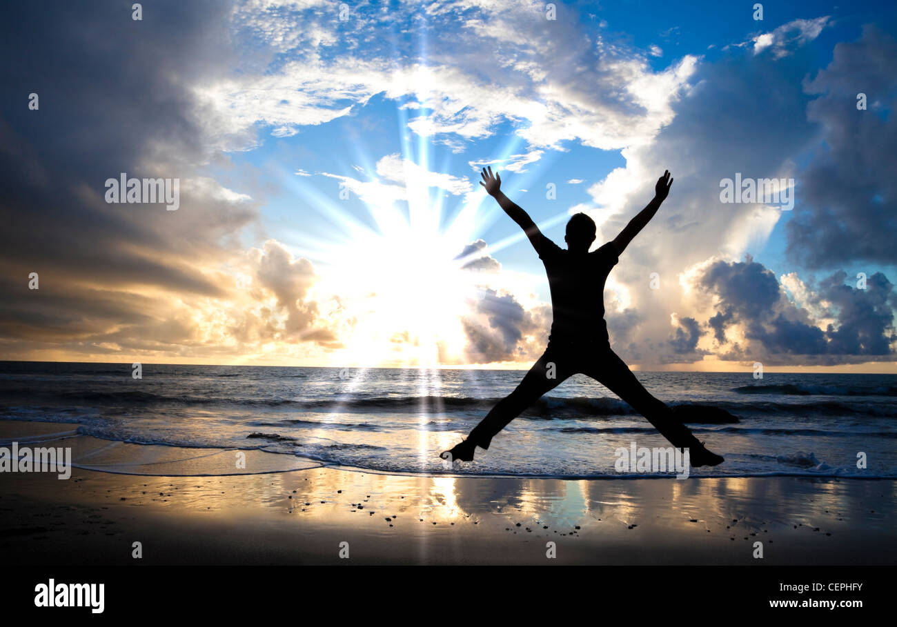 glücklicher Mann am Strand mit wunderschönen Sonnenaufgang springen Stockfoto